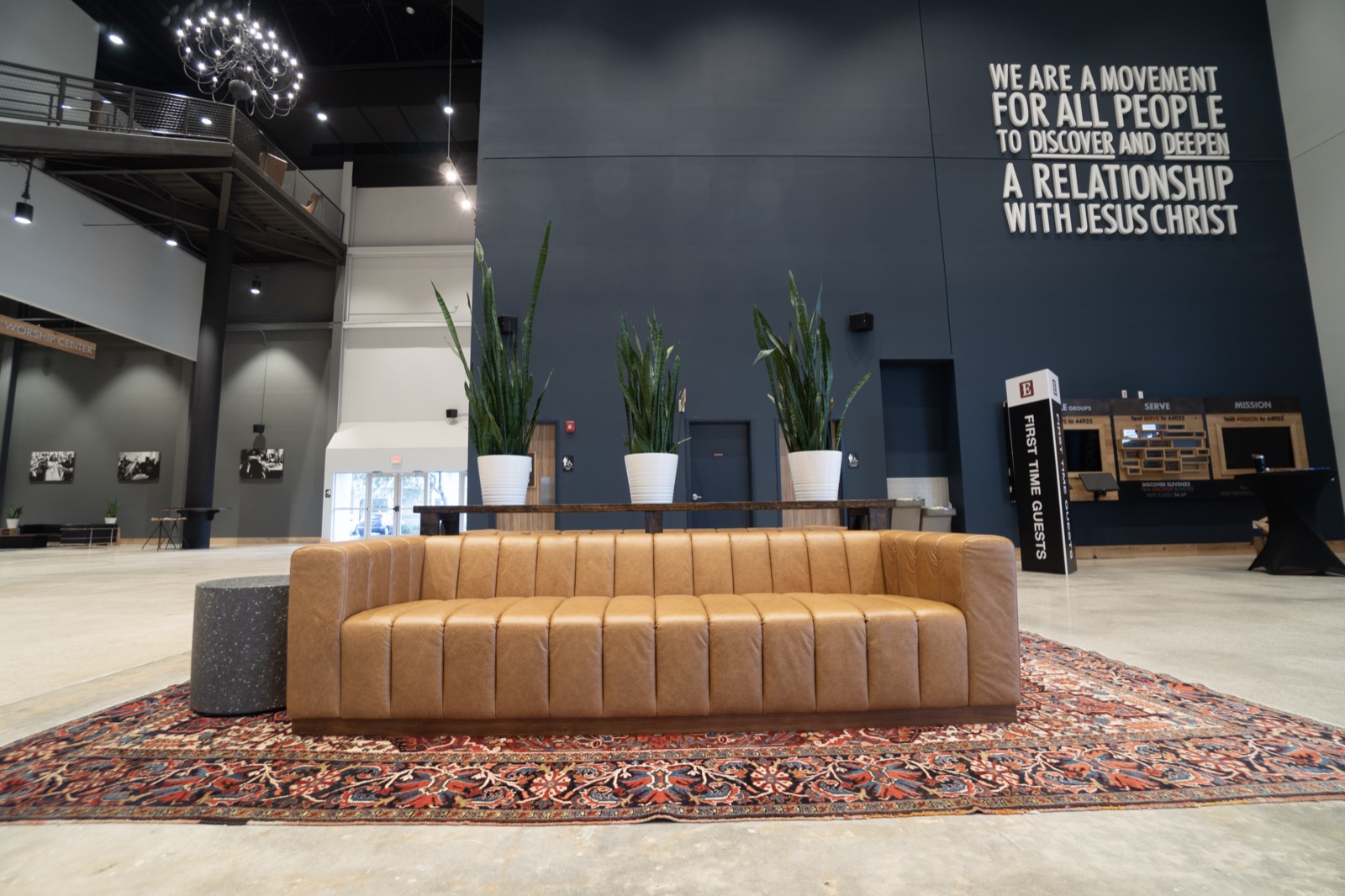 Church lobby with a painted mission statement wall: We are a movement for all people to discover and deepen a relationship with Jesus Christ